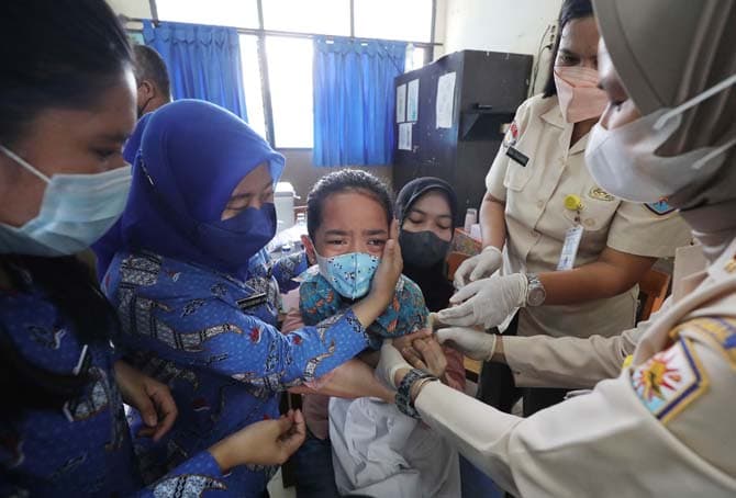 Vaksinator menyuntikkan vaksin COVID-19 dosis pertama kepada siswa di SD Plus Hang Tuah 06 di Jakarta, Rabu (22/12/2021). TNI AL melalui Lantamal III memberikan Vaksinasi anak usai 6 - 11 tahun Sebanyak 400 siswa dari Sekolah Dasar dan Sekolah Taman Kana - Image